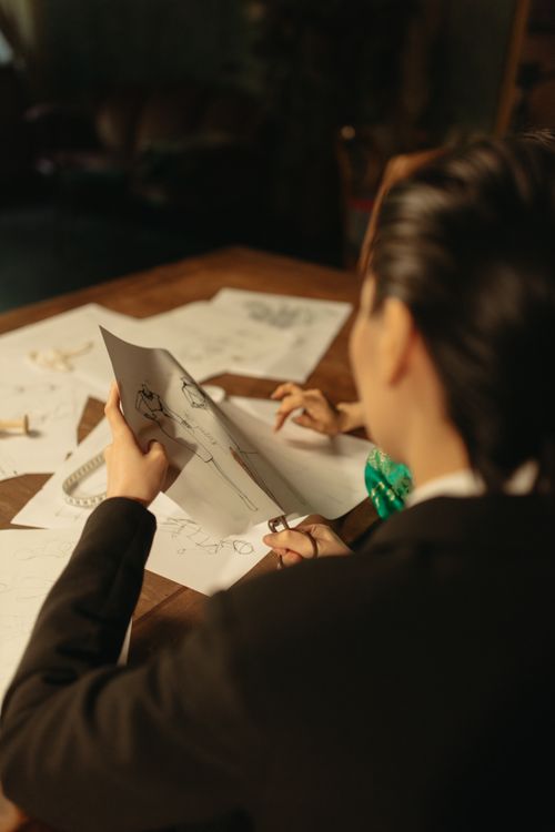 Free A fashion designer evaluating clothing sketches at a workshop desk. Stock Photo