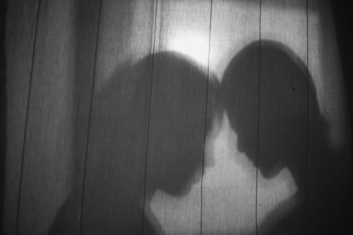 Free Intimate shadowy silhouette of a couple behind a curtain conveying romance and mystery. Stock Photo
