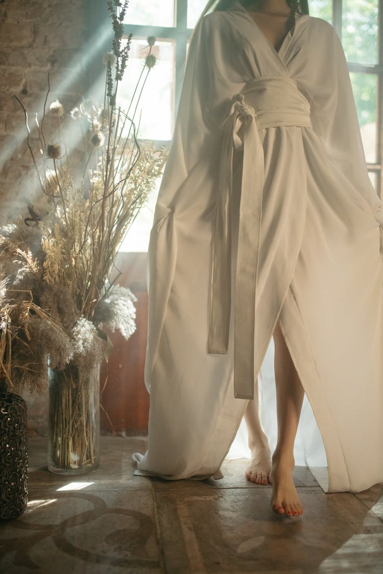 Person In White Robe Walking On Floor Tiles