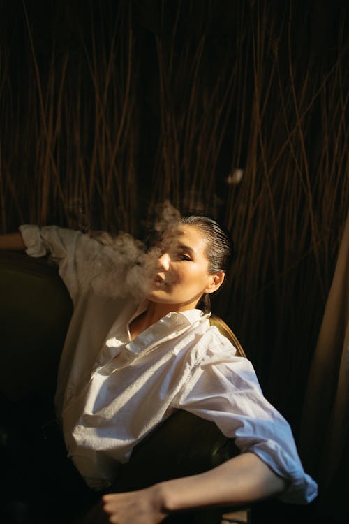 A Woman in White Long Sleeves Smoking