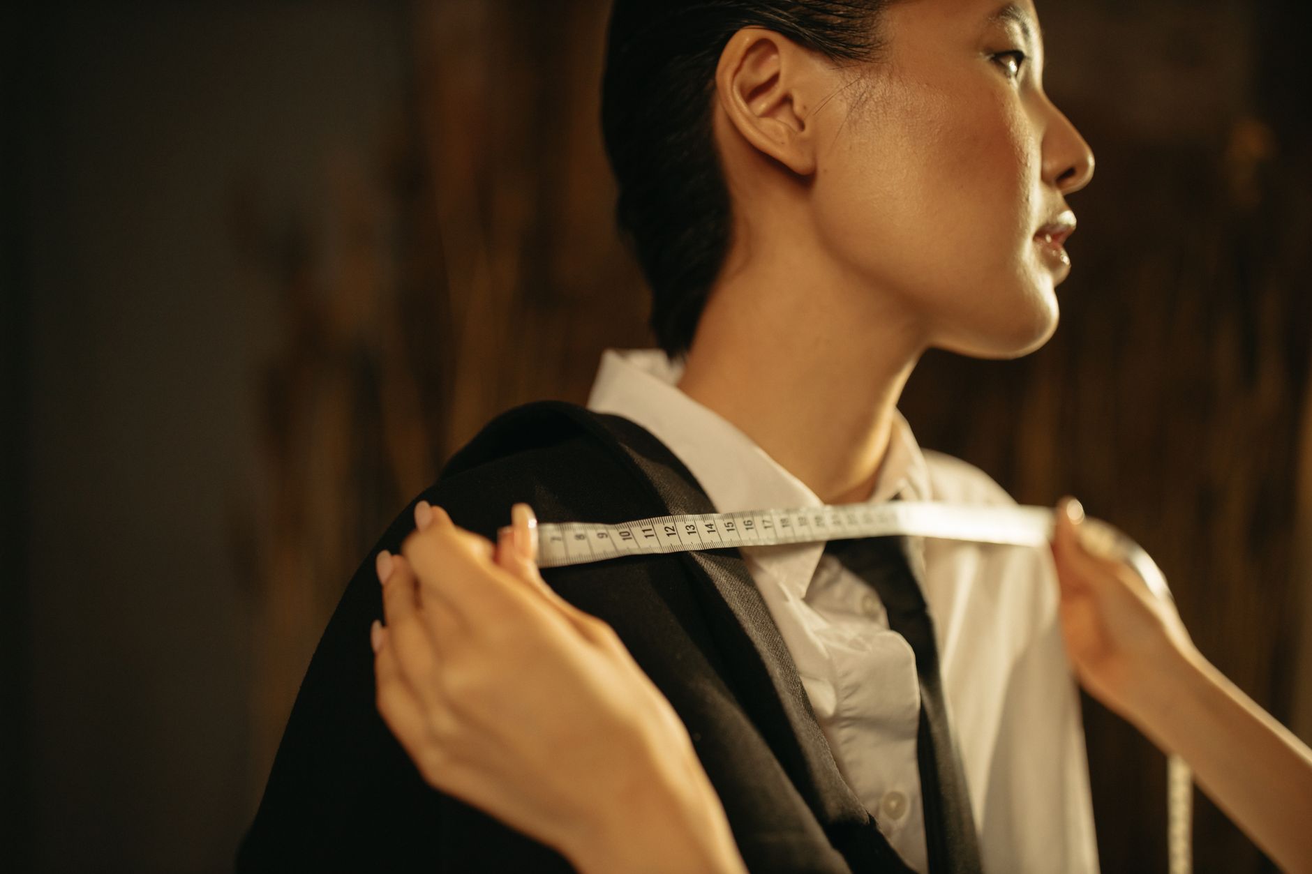 hands inspecting a blazer's interior shoulder seam with a measuring tool