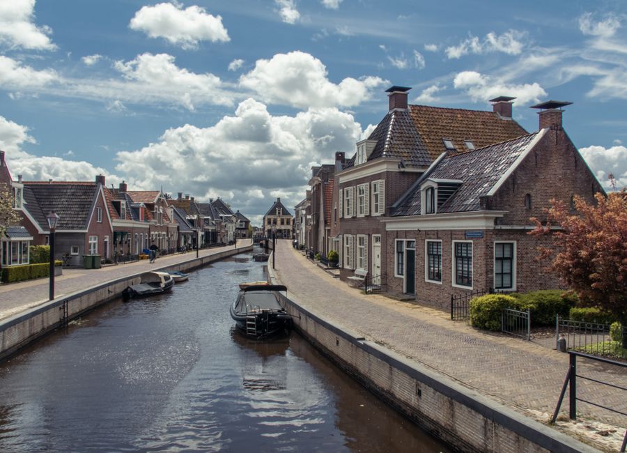 Charming village view of Kollum with canal and traditional houses under a blue sky.