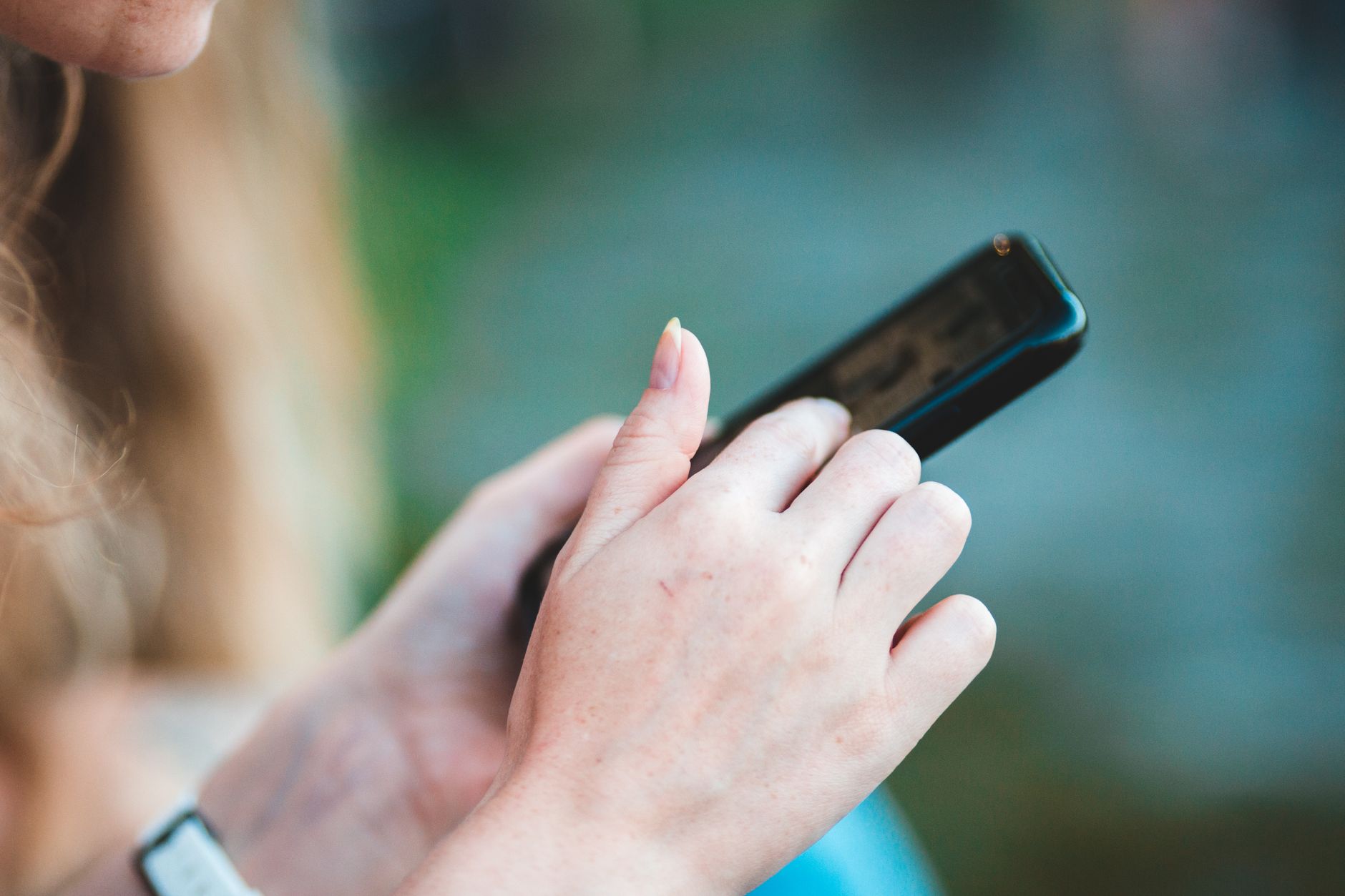 Hands holding a smartphone with blurred background, showcasing modern technology use.