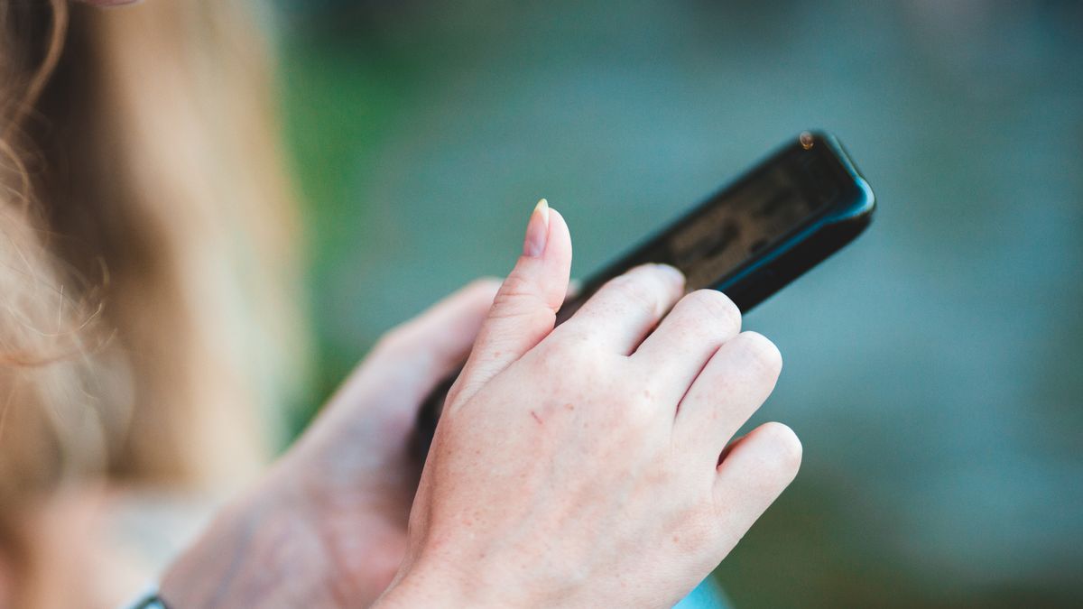 Hands holding a smartphone with blurred background, showcasing modern technology use.