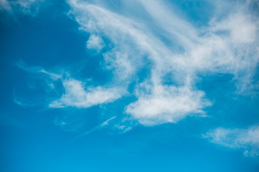 A serene sky scene featuring bright blue skies and fluffy white clouds in daylight.