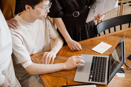 Asian man using a laptop during a team meeting. Collaborative work indoors.
