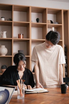 Two colleagues working together in an office, discussing ideas over a notebook.