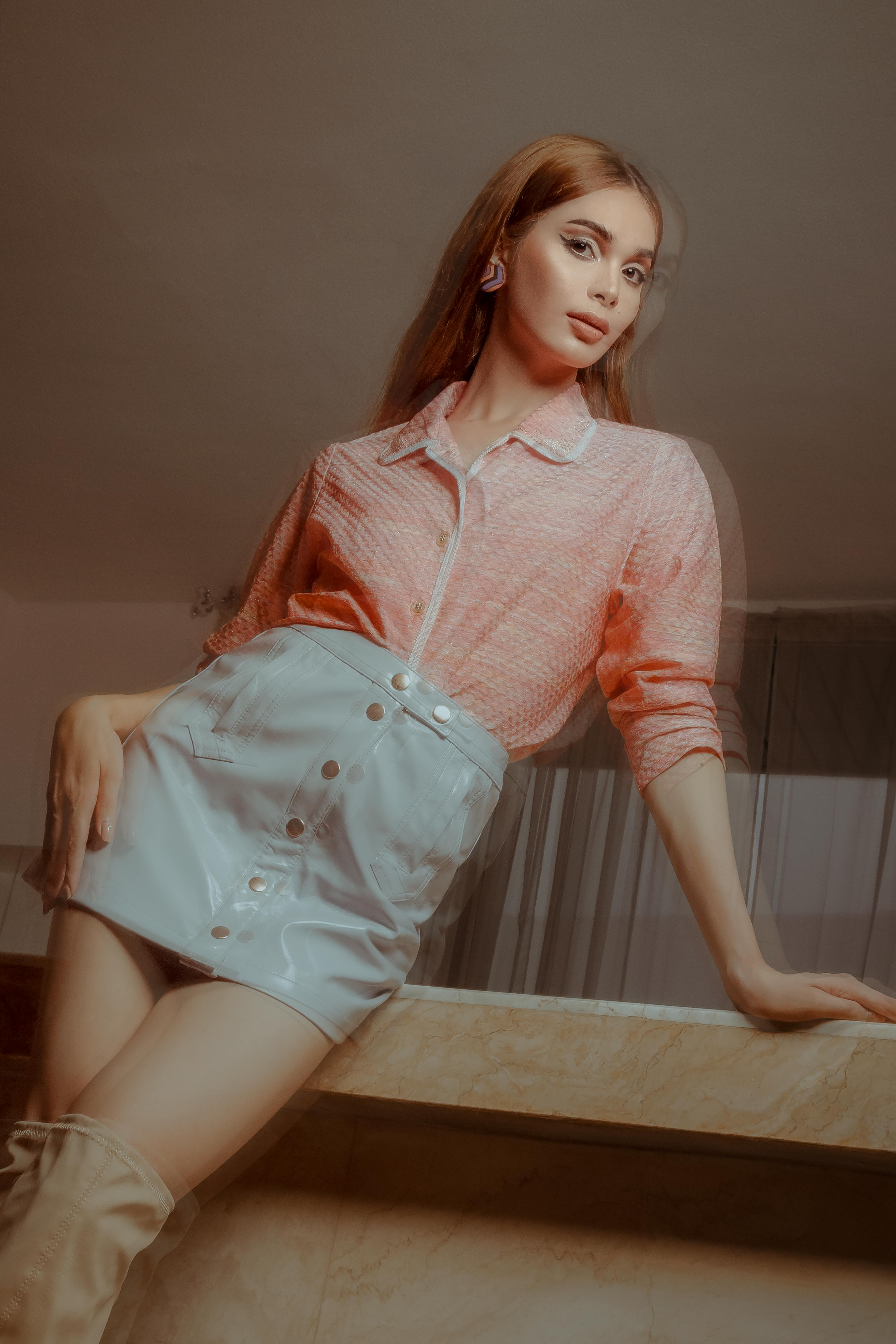 Young woman in stylish outfit posing indoors, exuding elegance and confidence.