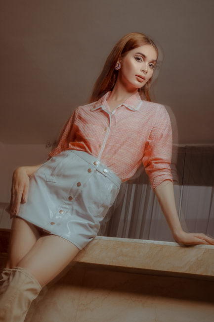 Young woman in stylish outfit posing indoors, exuding elegance and confidence.