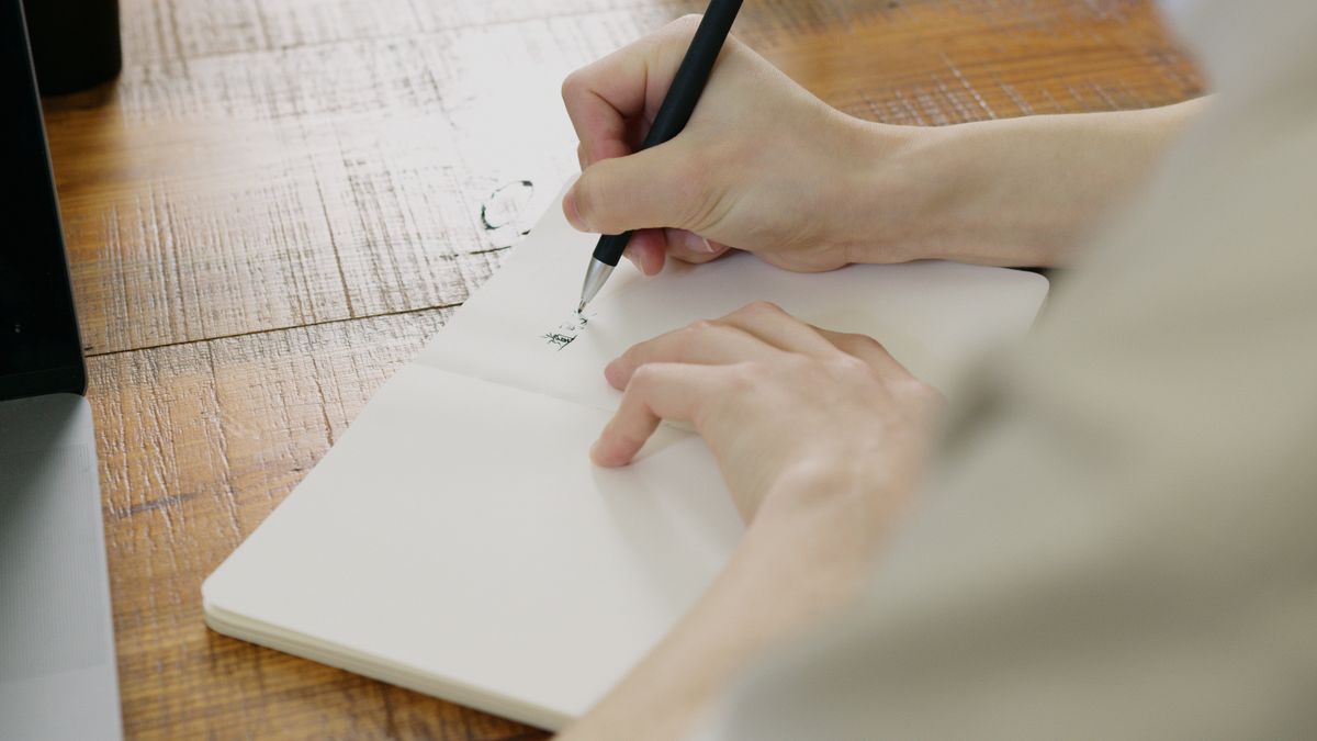 Une main qui écrit dans un carnet ouvert