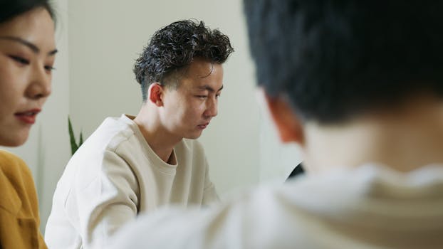 A focused group of adults in a business meeting room working on a project together.