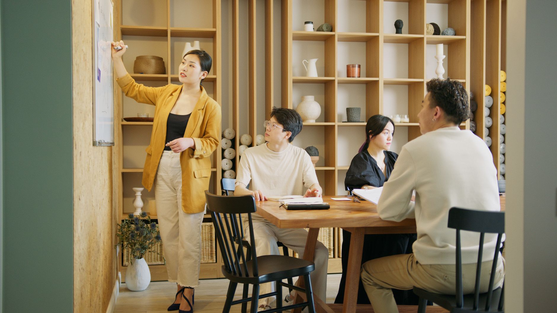 A group of professionals brainstorming and planning on a whiteboard in a stylish office setting.