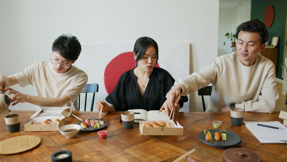 テーブルを囲んで食事をする三人