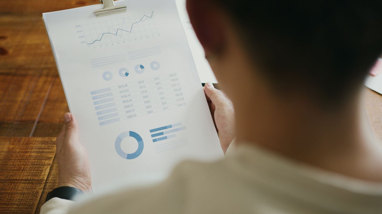 Free A person reviewing business performance data with charts on a clipboard in an office setting. Stock Photo