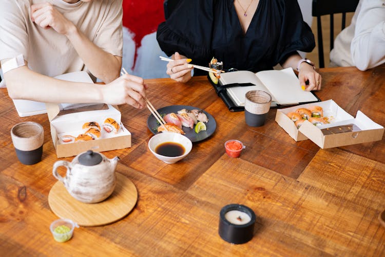 People Holding Chopsticks With Sushi