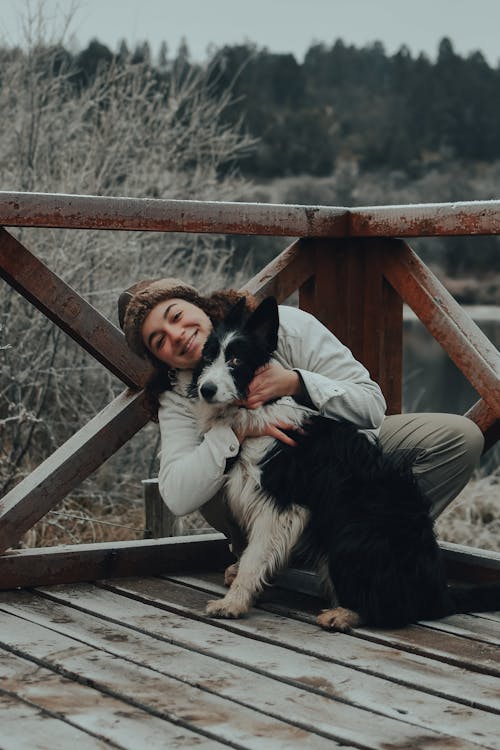 A Woman in White Jacket Embracing Her Dog