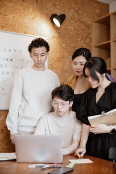 Group of four young professionals brainstorming together in a modern office environment.