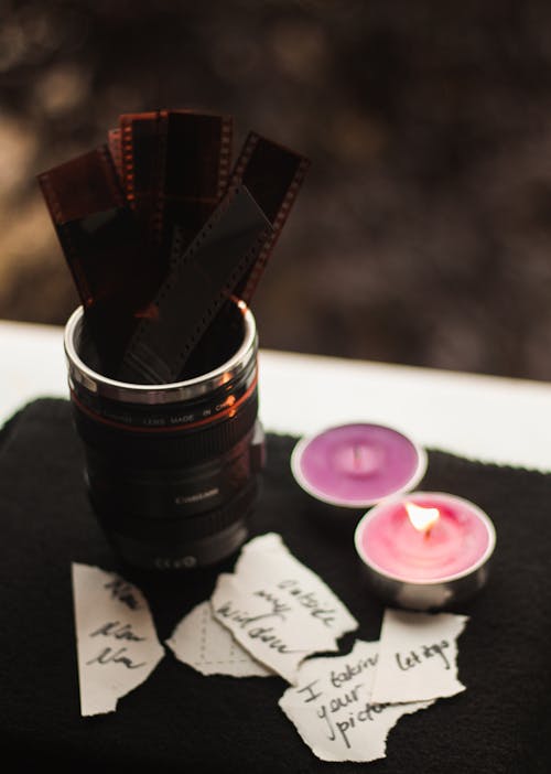 Close-up of Camera Lens and Films beside Candles
