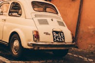 罗马的鹅卵石街道上，停着一辆经典的菲亚特500，给人一种复古的感觉