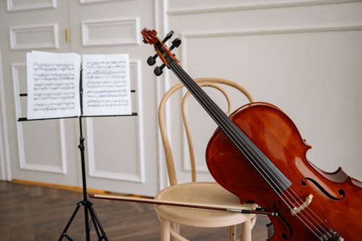 A cello and sheet music resting on a chair in an elegant, light-filled room.