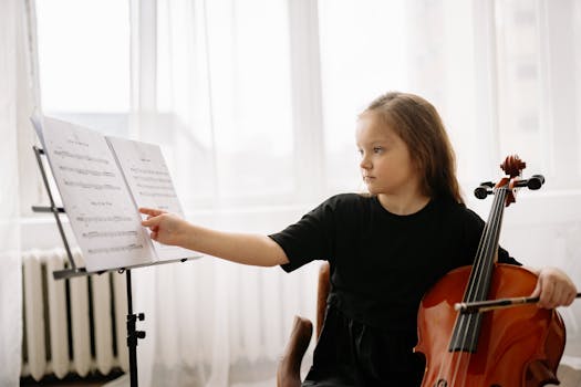 A young girl in a black shirt practices the cello with sheet music indoors.