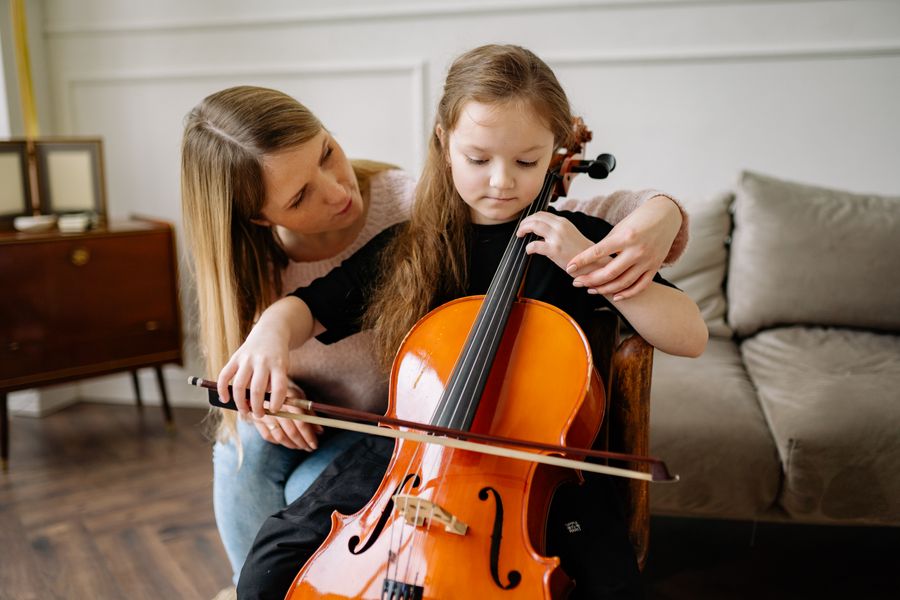 A volunteer teaching a Compass Club student to play cello