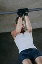 A Man in White Tank Top Holding on a Metal Bar while Wearing Black Gloves