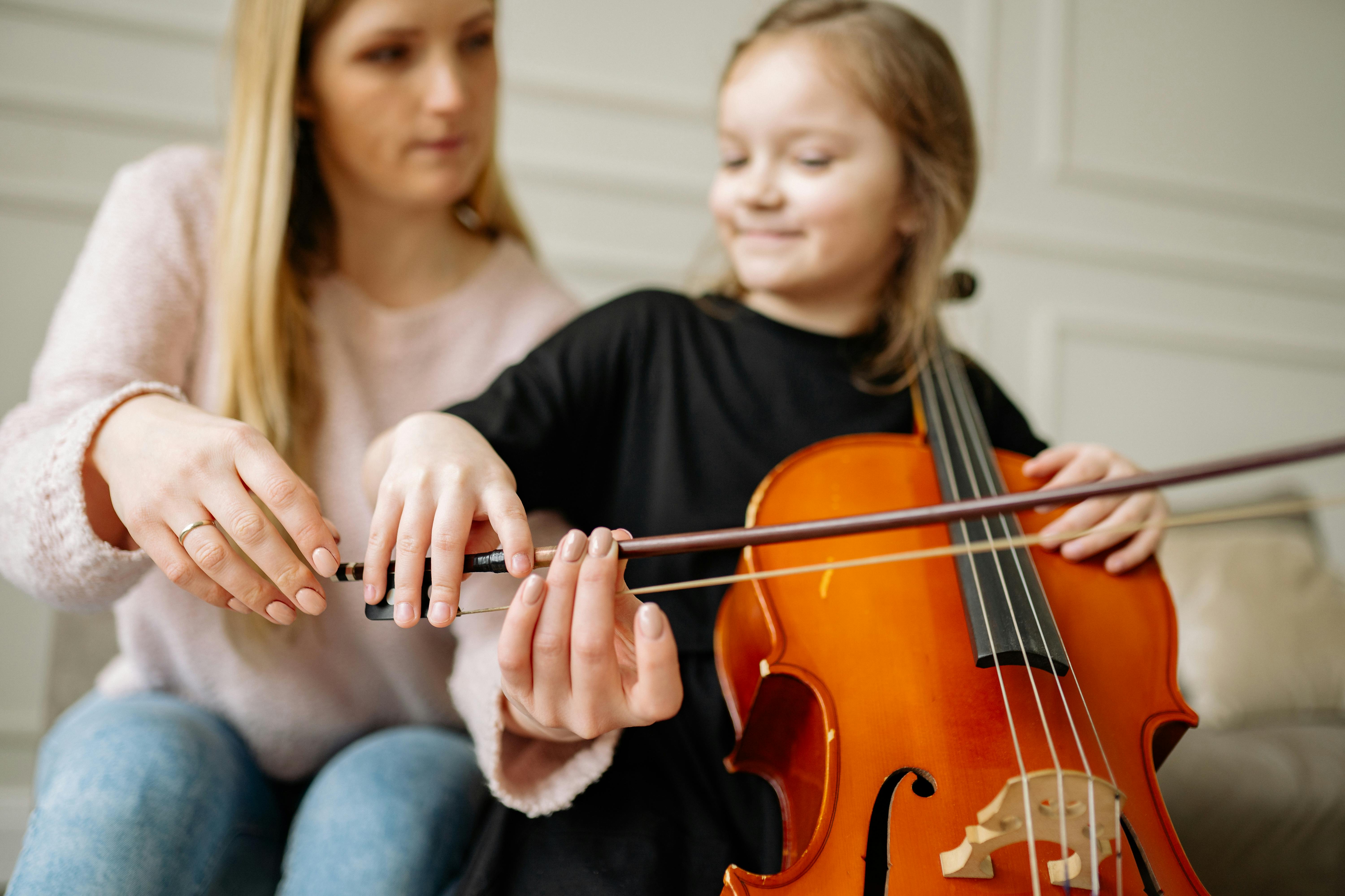 a woman teaching a girl how to play cello