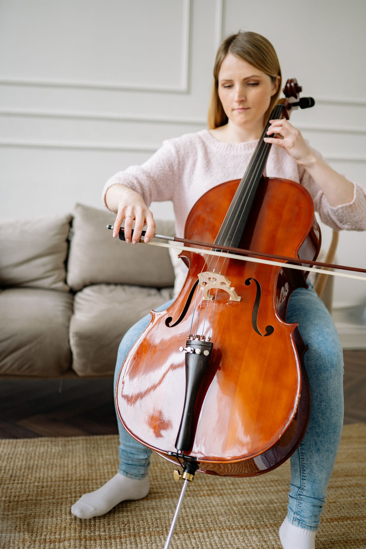 Adult woman playing a cello in a cozy indoor setting