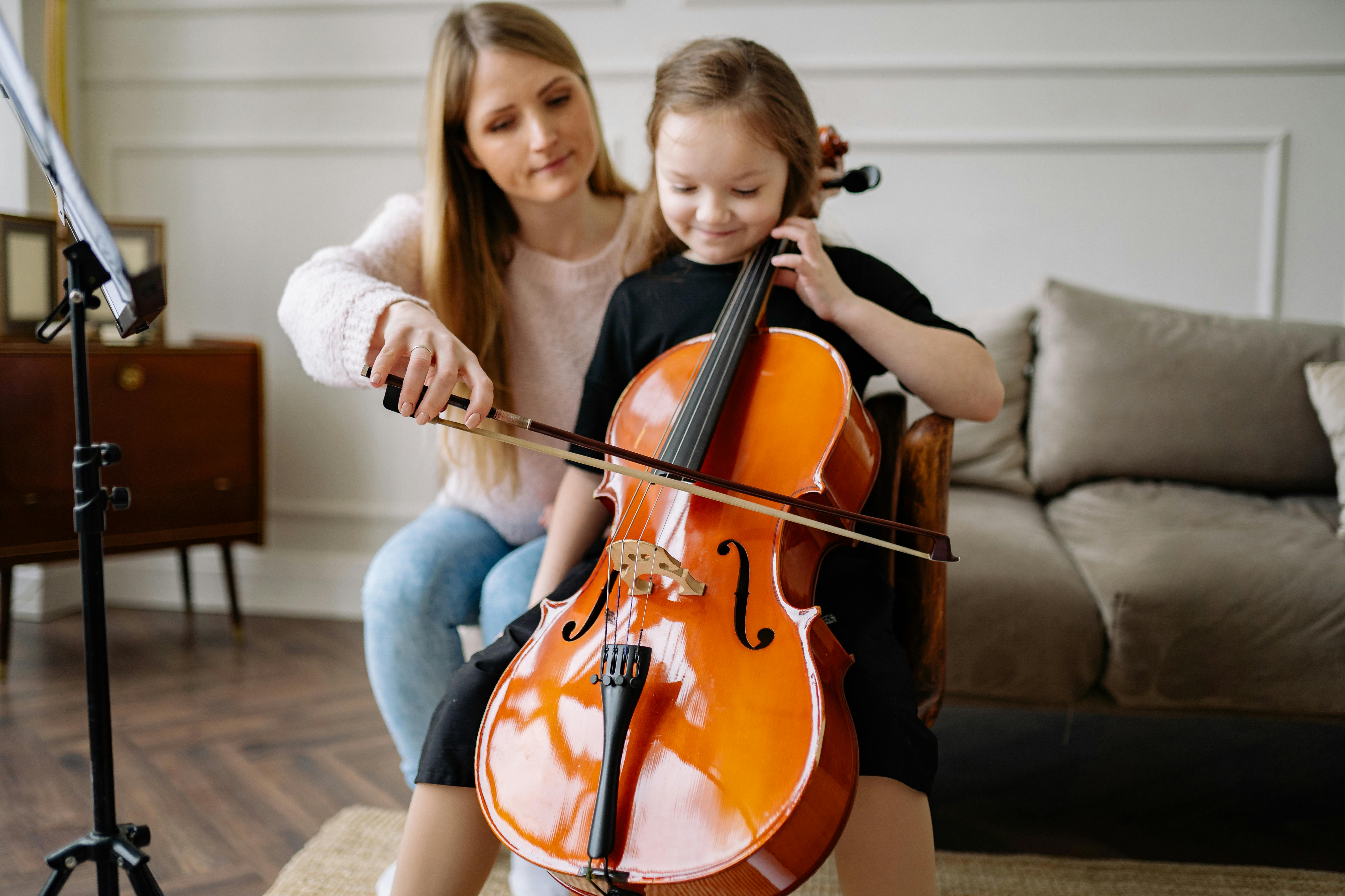 woman teaching a girl to play the cello