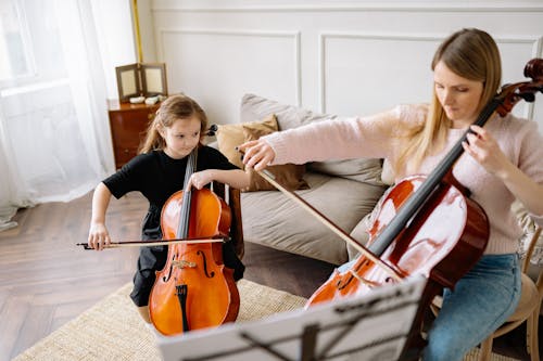 Woman and a Cute Girl Playing Cello Together