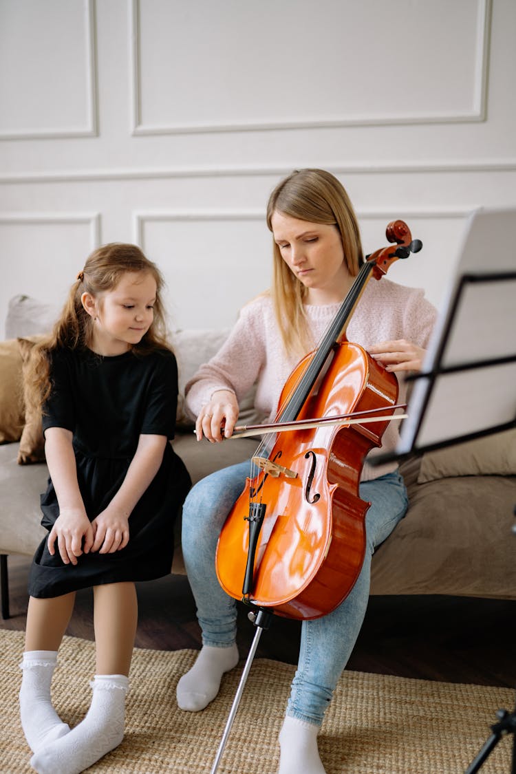 Music Teacher Playing A Cello Beside A Child