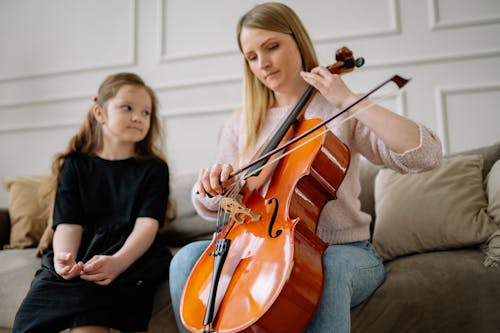 Woman Playing Cello in Front of Girl