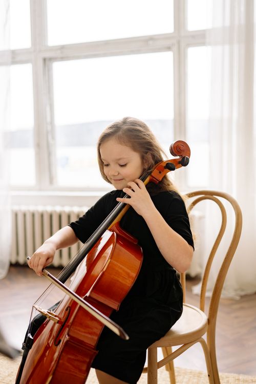Free A young girl passionately playing the cello indoors, showcasing musical talent. Stock Photo