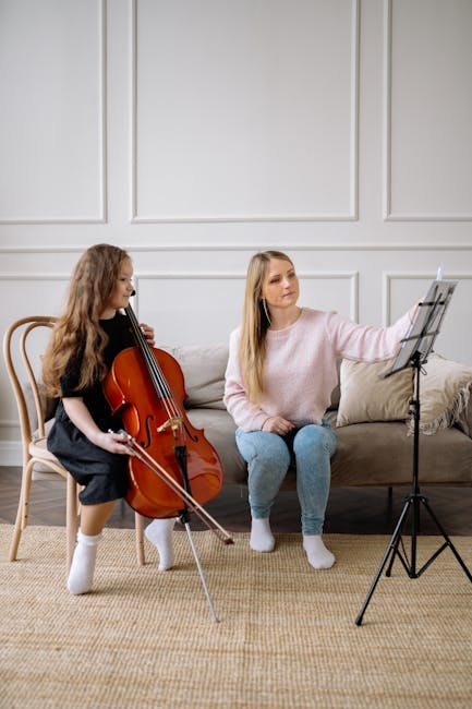 A young girl is learning to play the cello with her teacher at home.