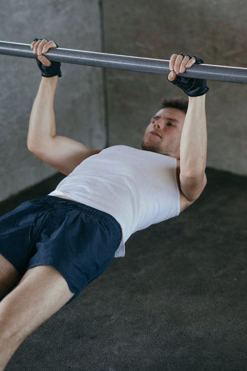 Free A Man in White Tank Top Working Out while Wearing Fingerless Gloves Stock Photo