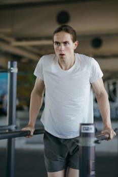 Focused young man working out indoors, showcasing strength and determination in a gym setting.