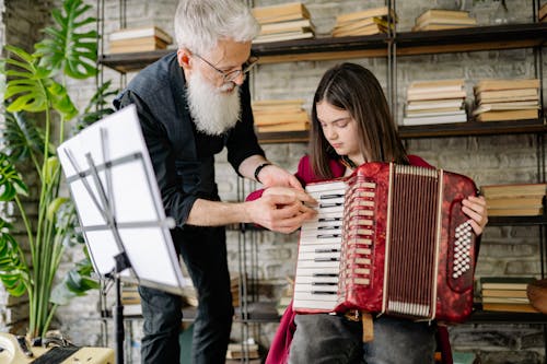 A Man Teaching a Girl How to Play Accordions