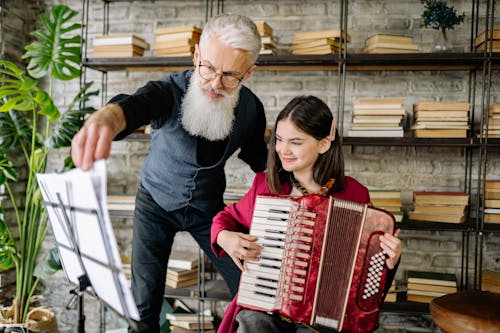 A Man Teaching a Girl How to Play an Accordion