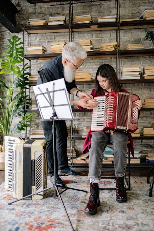 A Man Teaching a Girl How to Play an Accordion