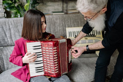 A Man Teaching a Girl How to Play an Accordion