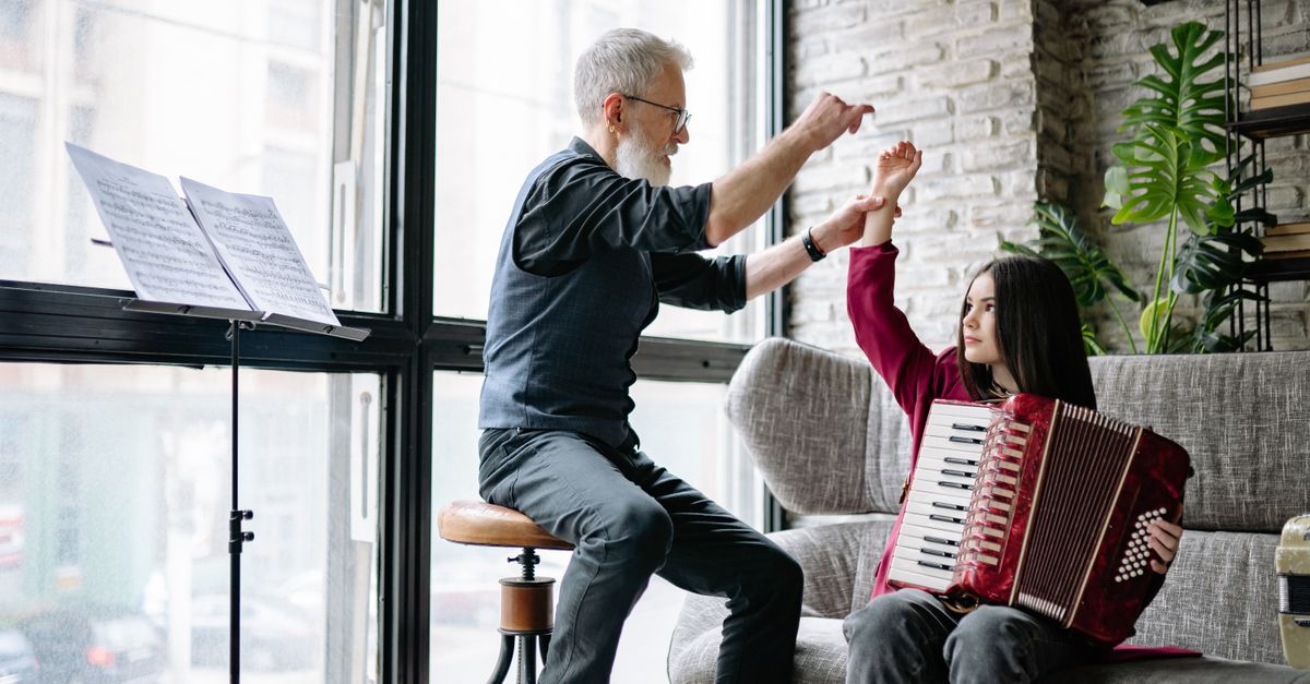 music teacher and student laughing together, instruments in hands, casual setting