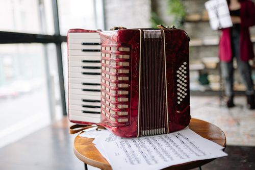 Free A vibrant red accordion and sheet music on a stool in an indoor setting. Stock Photo