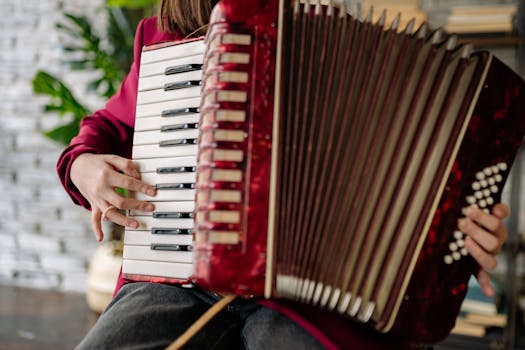 Musician's hands playing an accordion indoors with focus on keys and buttons.