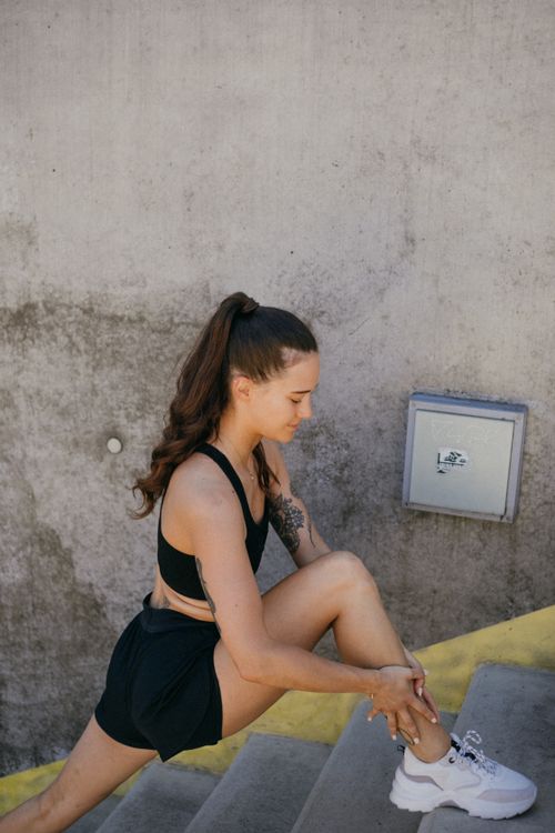Free Athletic woman doing a lunge stretch on outdoor stairs for fitness training. Stock Photo