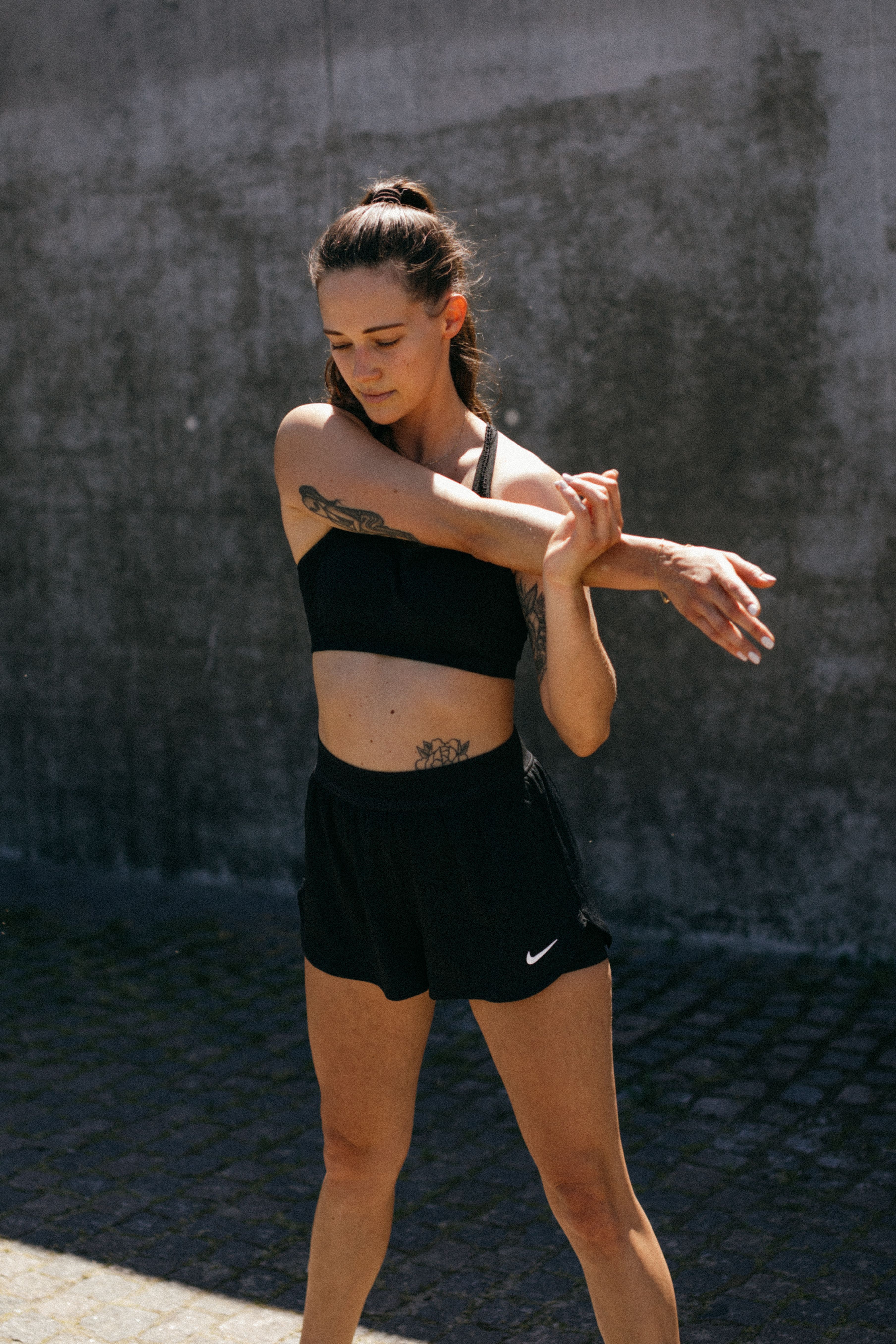 Woman in activewear stretching outdoors, promoting fitness and healthy living.