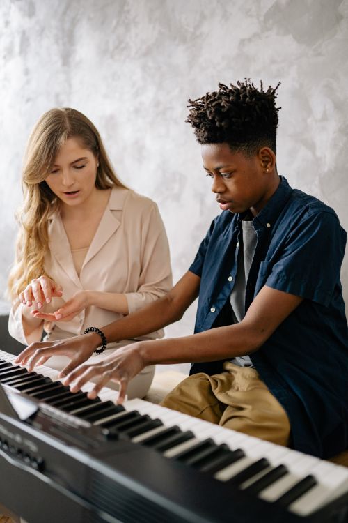 Free A young boy being guided by a female teacher during his piano lesson. Stock Photo