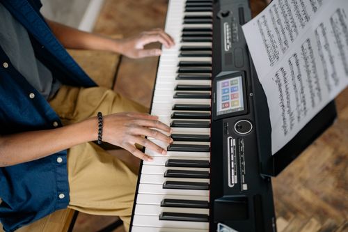 Free A person playing an electric piano with sheet music. High angle view. Indoor setting. Stock Photo
