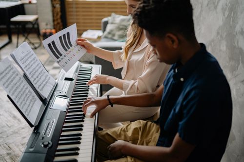 Free A young boy learns piano with a female teacher, engaging in a music lesson indoors. Stock Photo
