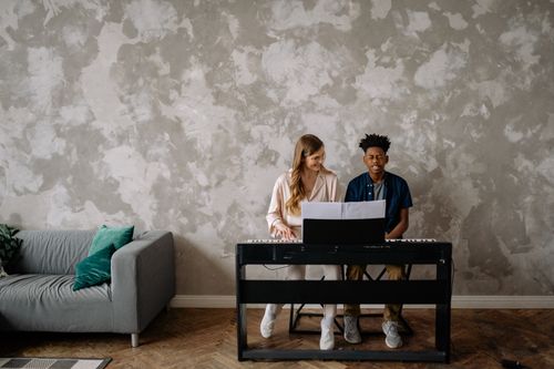 Free A woman and teenager enjoying a piano lesson in a stylish living room. Stock Photo